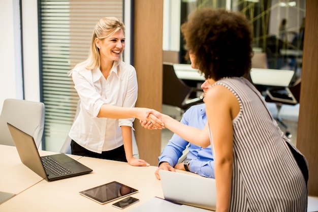 Dois jovens empresárias apertando as mãos depois de um trabalho bem feito