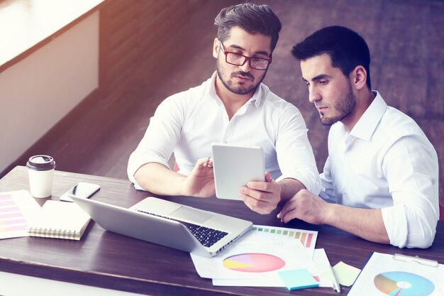 Dois jovens empresários trabalhando em um laptop em um escritório moderno. efeito de filme, reflexo de lente