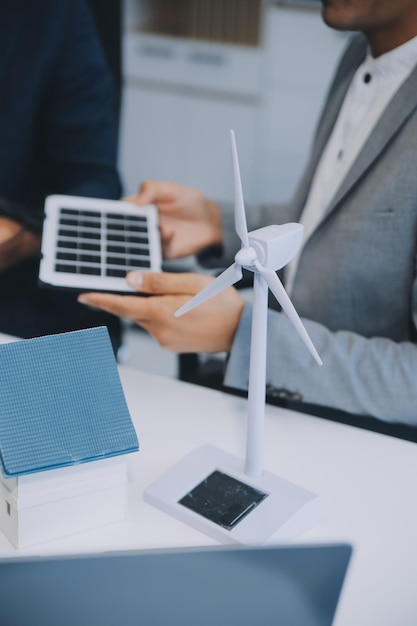 Foto dois jovens engenheiros especializados na instalação de células solares reuniões e discussão no trabalho planejamento para instalar painéis fotovoltaicos solares no telhado da sala de escritórios com plano de construção da fábrica