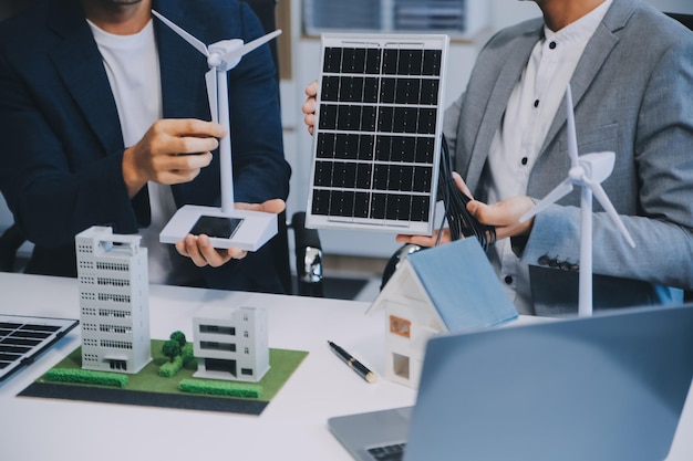 Dois jovens engenheiros especializados na instalação de células solares Reuniões e discussão no trabalho Planejamento para instalar painéis fotovoltaicos solares no telhado da sala de escritórios com plano de construção da fábrica