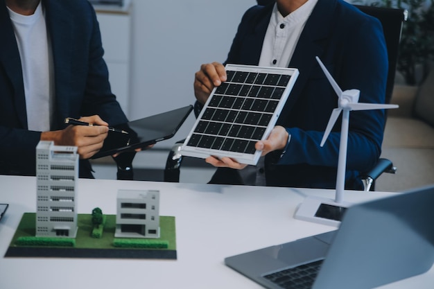 Dois jovens engenheiros especializados na instalação de células solares Reuniões e discussão no trabalho Planejamento para instalar painéis fotovoltaicos solares no telhado da sala de escritórios com plano de construção da fábrica