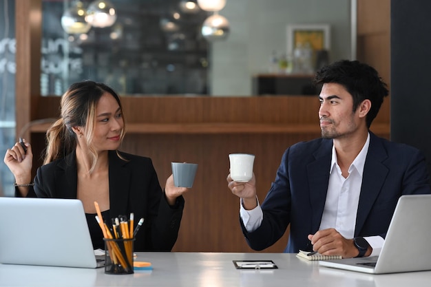 Dois jovens gerentes bebendo café e conversando durante o intervalo no escritório brilhante