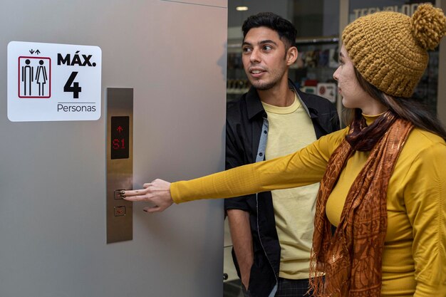 Dois jovens irmãos latino-americanos no shopping esperam o elevador ela aperta o botão ambos vestem amarelo movimento de conceito