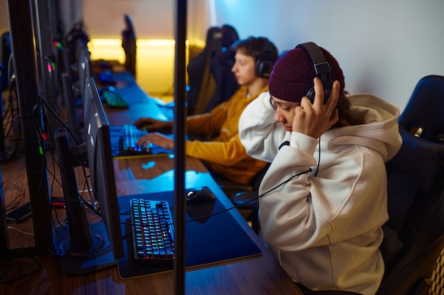 Dois jovens jogadores em fones de ouvido jogam no clube de videogame