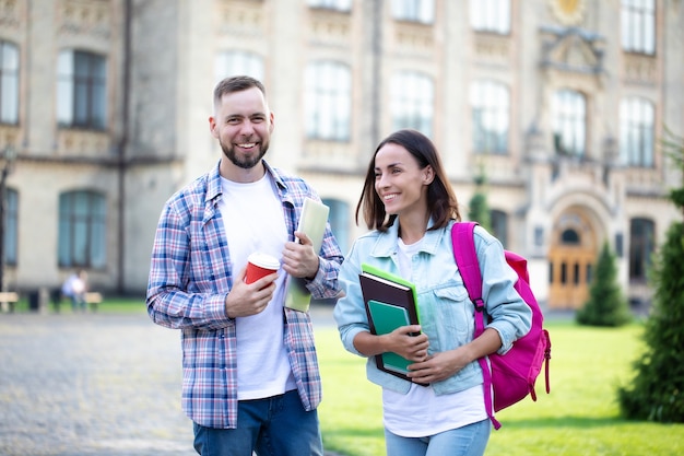 Dois jovens melhores amigos da universidade com roupas casuais e mochila conversando no campus e rindo