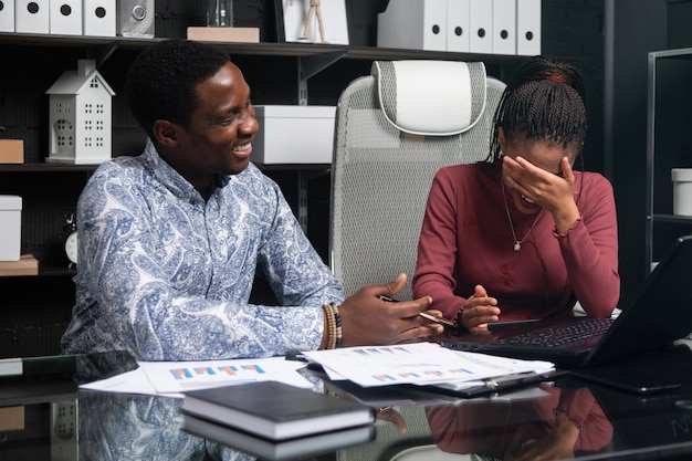 Dois jovens negros rindo se divertem discutindo seus negócios sentado à mesa no escritório