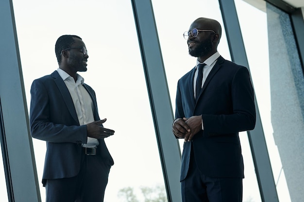 Dois jovens parceiros de negócios confiantes em ternos elegantes discutindo pontos de trabalho