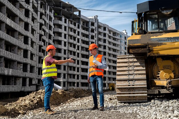 Dois jovens trabalhadores de uniforme estão considerando um projeto para construir uma nova casa