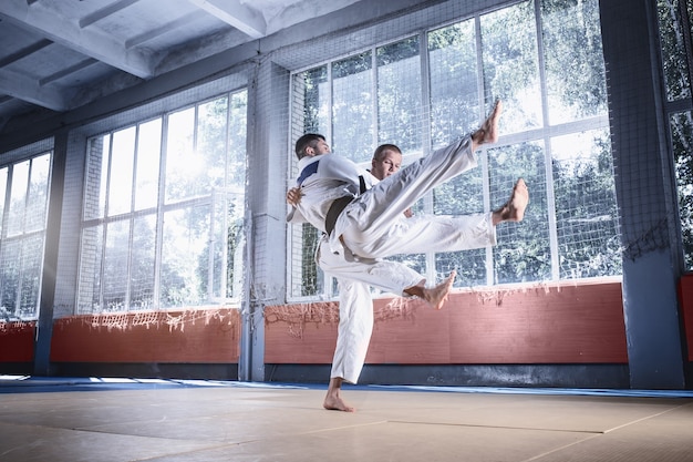 Dois judocas demonstrando habilidade técnica enquanto praticavam artes marciais em um clube de luta. os dois são homens uniformizados. luta, caratê, treinamento, artes, atleta, conceito de competição