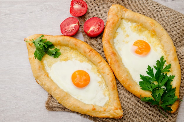 Dois khachapuri com ovo, salsa e tomate de saco, vista superior