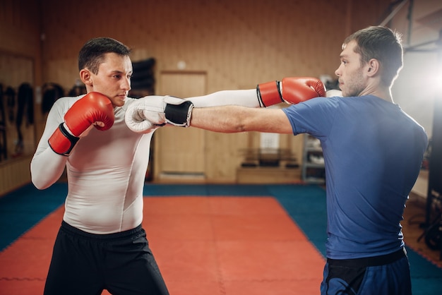 Dois kickboxers masculinos treinando na academia