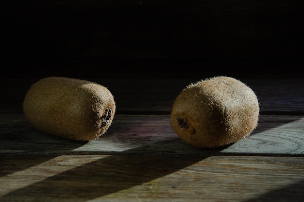 Dois kiwis inteiros em uma mesa de madeira de cozinha.