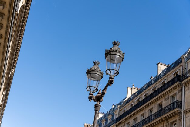 Dois lampiões de rua são acesos durante o dia lançando um brilho quente nos edifícios