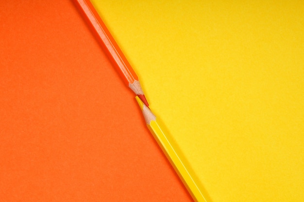 Dois lápis de cor isolados em um fundo de papel de duas cores diferentes