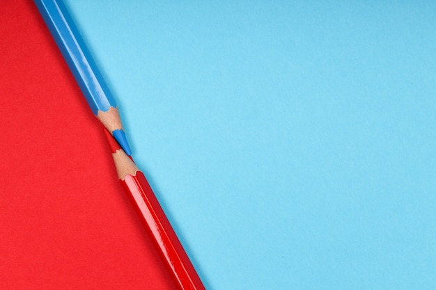 Dois lápis de cor isolados em um fundo de papel de duas cores diferentes
