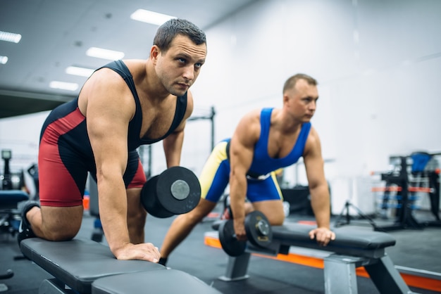 Dois levantadores de peso fazendo exercícios com halteres