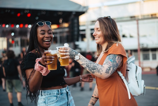 Foto dois lindos amigos bebendo cerveja e se divertindo no festival de música