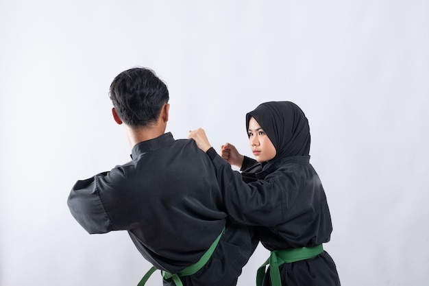 Dois lutadores com uniforme pencak silat Hitam lutando em um empurrão no branco