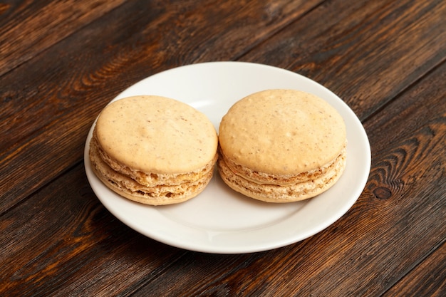 Dois macarons de chocolate franceses tradicionais no prato, mesa de madeira