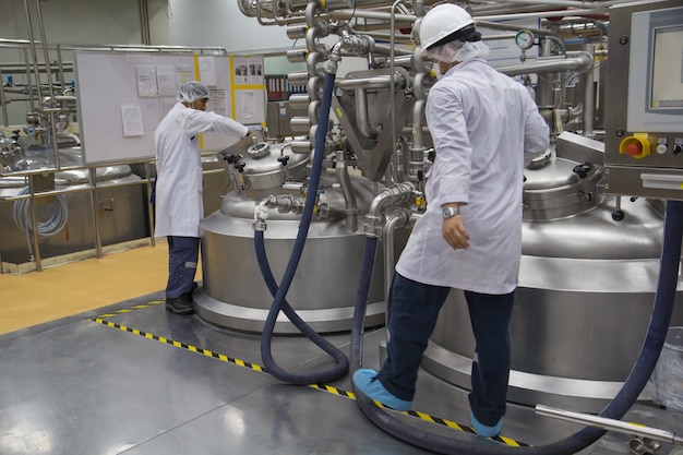 Foto dois machos trabalham o processo de fermentação cosmética de creme na fabricação com tanque de inox