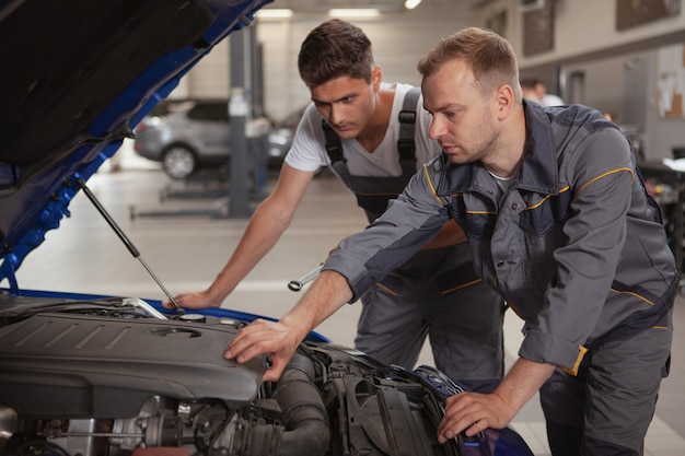 Dois mecânicos masculinos trabalhando na garagem