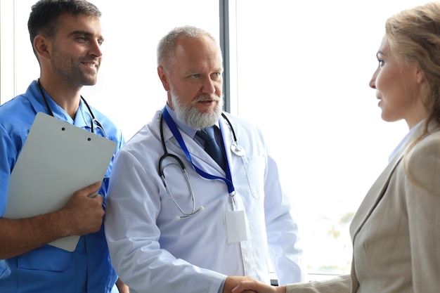 Dois médicos e pacientes do sexo feminino apertando as mãos antes da consulta no escritório de um centro médico moderno.