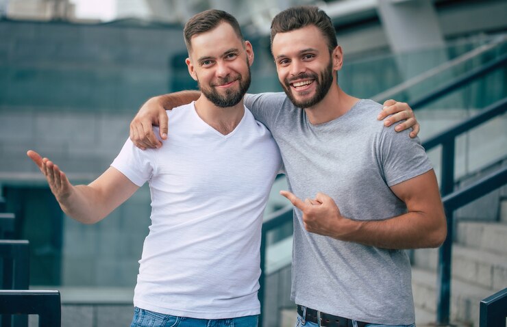 Foto dois melhores amigos barbudos bonitos animados felizes em roupas casuais estão apertando a mão, abraçando-se ao ar livre.