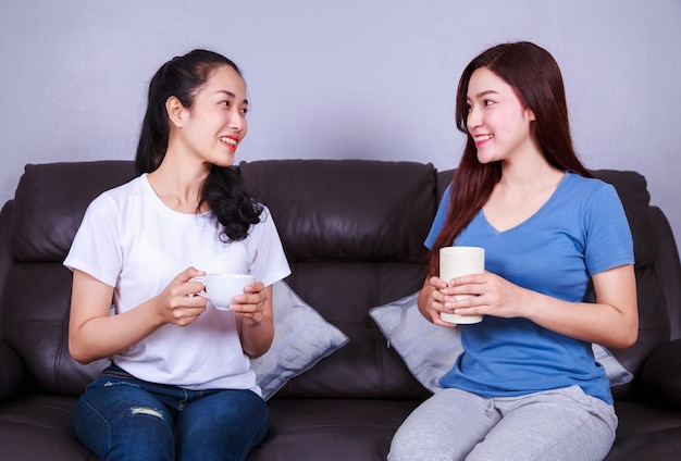 dois melhores amigos conversando e tomando uma xícara de café no sofá na sala de estar