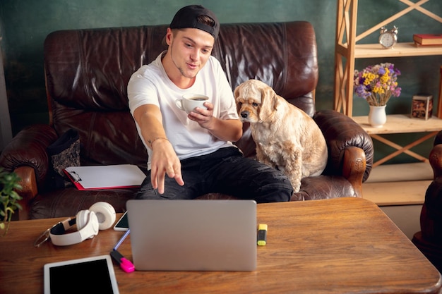 Dois melhores amigos jovem e americano Cocker Spaniel cor creme bebem chá em casa.