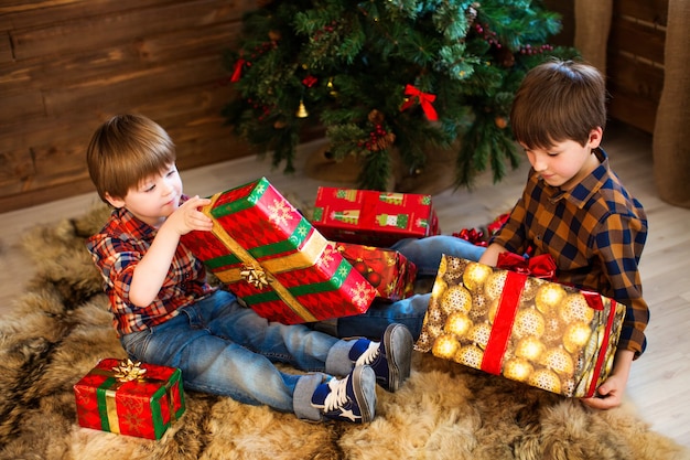 Dois meninos adoráveis abrindo presentes no natal