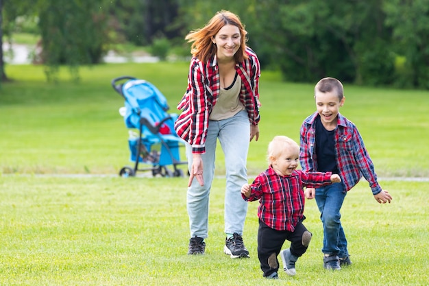 Dois meninos alegres bonitos irmão criança com mãe brincar ao ar livre no parque.