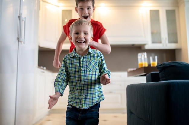 Dois meninos alegres correndo pela casa