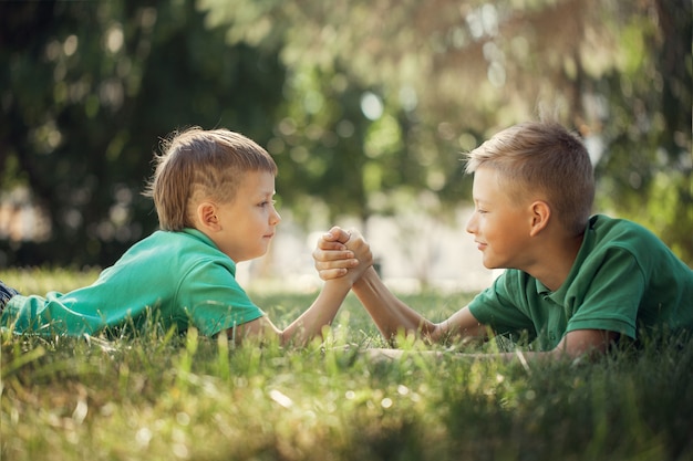 Dois meninos, apertou mãos, acoplado, um, braço wrestle, ligado, gramado verde, em, verão