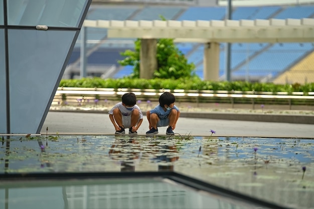 Dois meninos asiáticos brincando perto da fonte em singapura