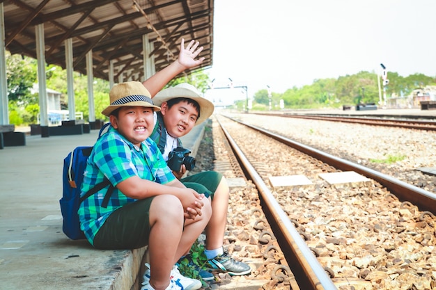 Dois meninos asiáticos sentado no trem esperando para viajar