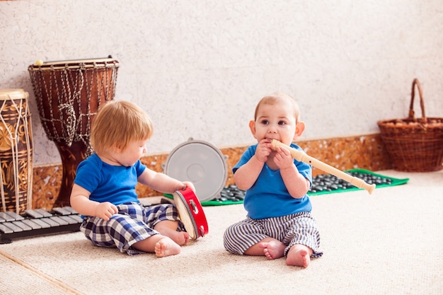 Dois meninos brincando com entusiasmo com vários instrumentos musicais