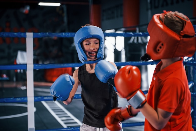 Dois meninos com equipamentos de proteção lutam e lutam no ringue de boxe.