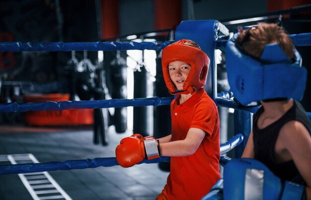 Dois meninos com equipamentos de proteção lutam e lutam no ringue de boxe.