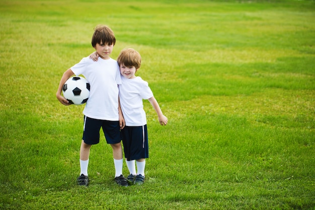 Dois meninos com uma bola de futebol em um campo de futebol