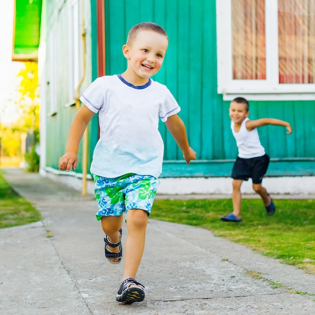 Dois meninos correm e brincam no quintal perto de casa em um dia de verão