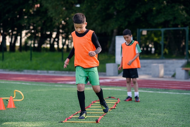 Dois meninos da escola estão executando exercícios de escada durante o acampamento de verão de futebol.