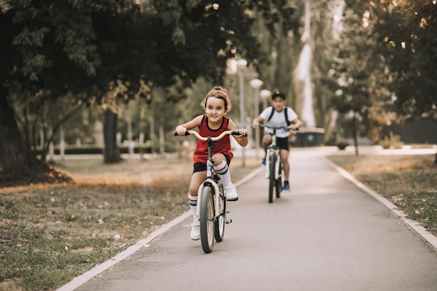 Dois meninos e meninas ciclistas andando de bicicleta e gostam de se divertir Criança ao ar livre atividade de verão