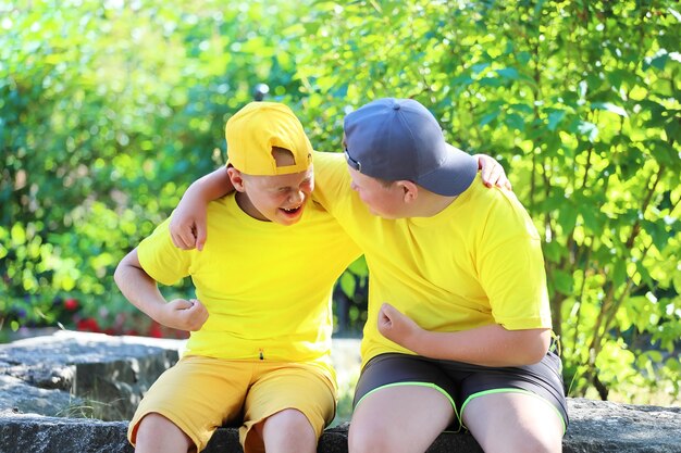 Dois meninos em camisetas amarelas se abraçando sentado no parque. Foto de alta qualidade