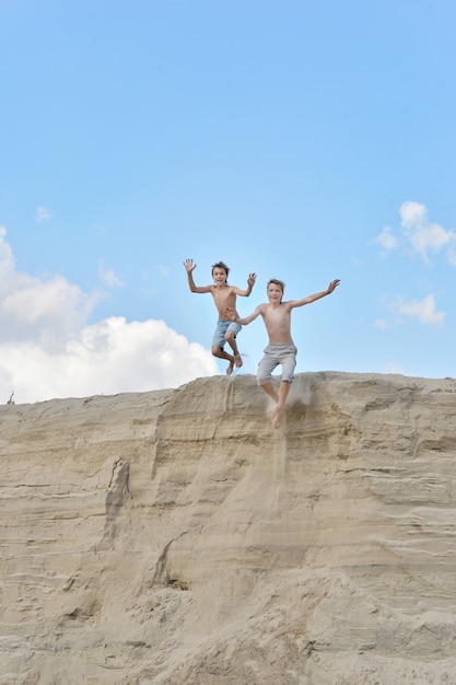 Dois meninos em uma colina de areia contra o céu