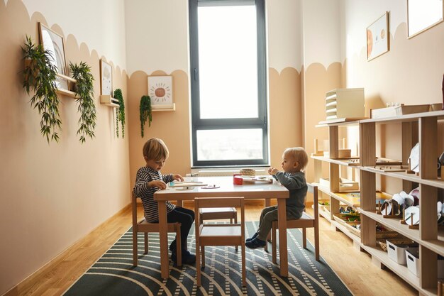 Foto dois meninos estão sentados à mesa e aprendendo com o uso de brinquedos educativos na sala de jogos