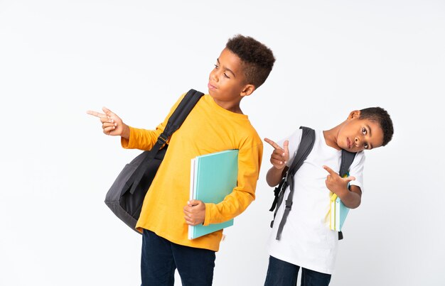 Dois meninos estudantes afro-americanos sobre branco isolado e apontando para a lateral