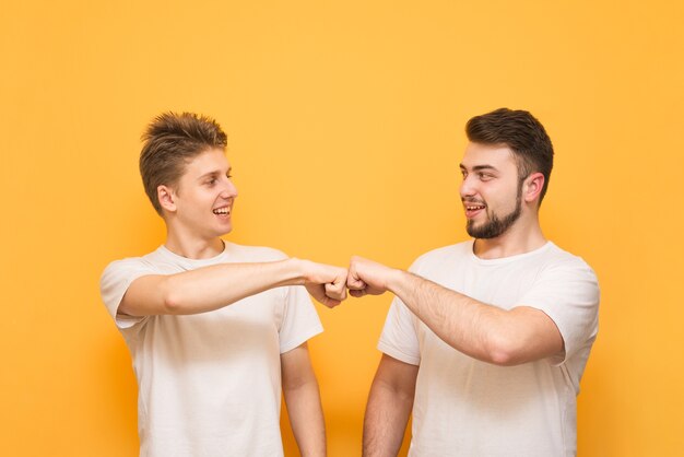 Foto dois meninos felizes em camisetas brancas fecham o punho e sorriem