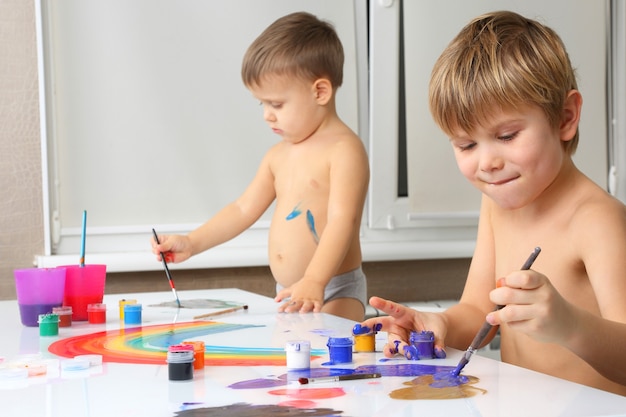 Dois meninos pintando em uma mesa branca