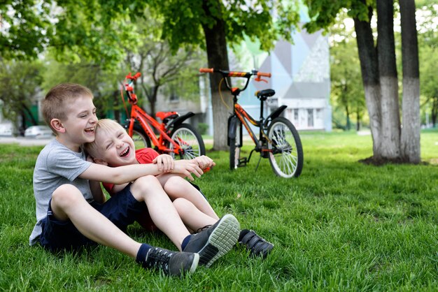 Dois meninos rindo se divertindo na grama. bicicletas