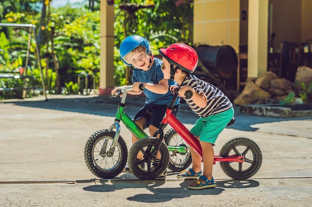 Dois meninos se divertindo em uma bicicleta Balance em uma estrada tropical